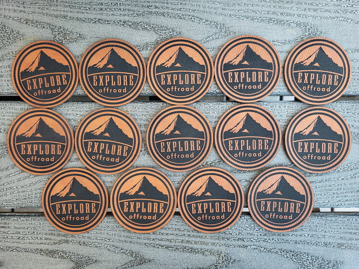 Sixteen round stickers with a mountain graphic and the text 'EXPLORE offroad' arranged in three rows on a weathered gray wood background.