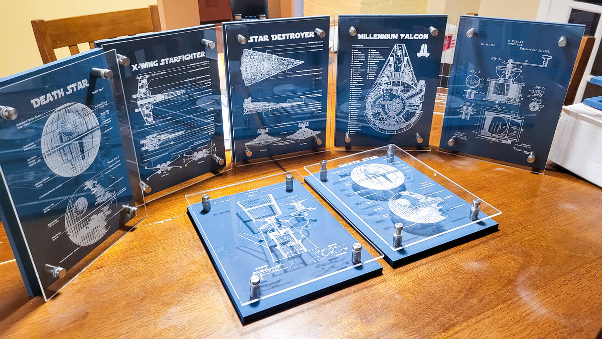 Six blue acrylic art prints featuring Star Wars spacecraft and ship designs, including Death Star, X-Wing Starfighter, Star Destroyer, Millennium Falcon, and Illionium Valkor, displayed on a wooden table with two mounted prints in front.